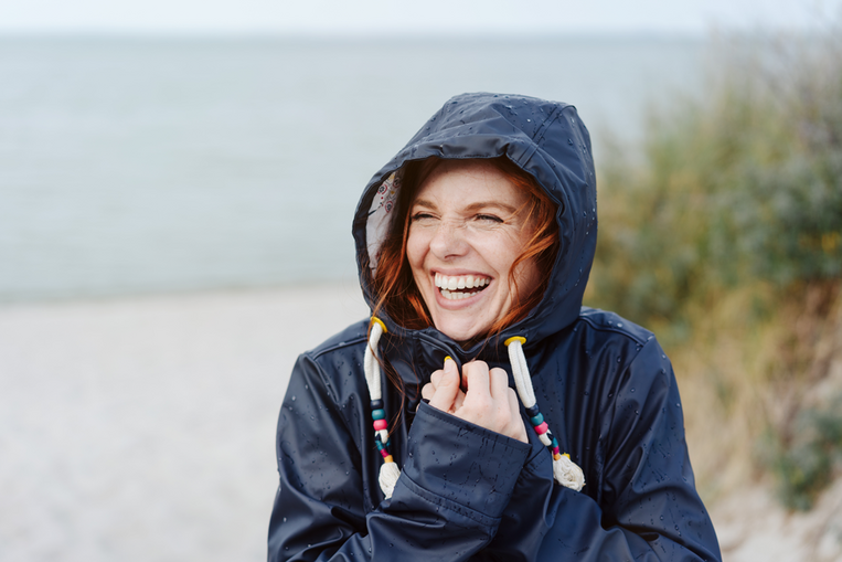 Frau in Regenjacke steht am Strand So stärken Sie Ihr Immunsystem