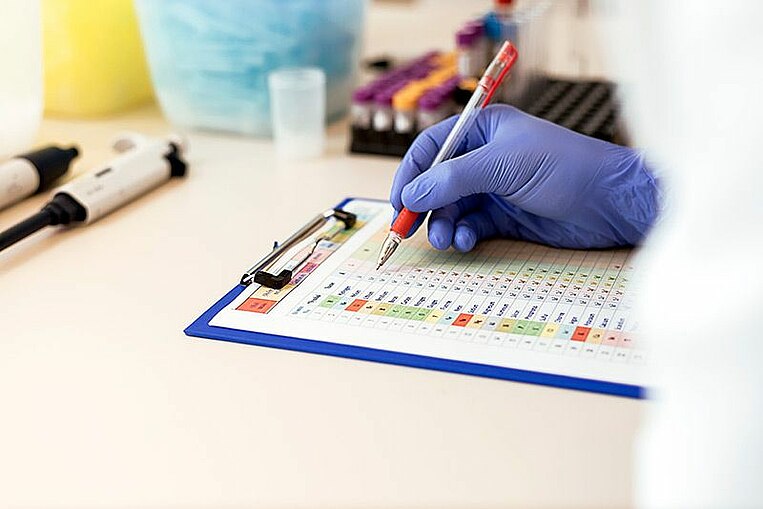 Laborant notiert etwas auf einem bunten Test-Bogen Laborant notiert etwas auf einem bunten Test-Bogen