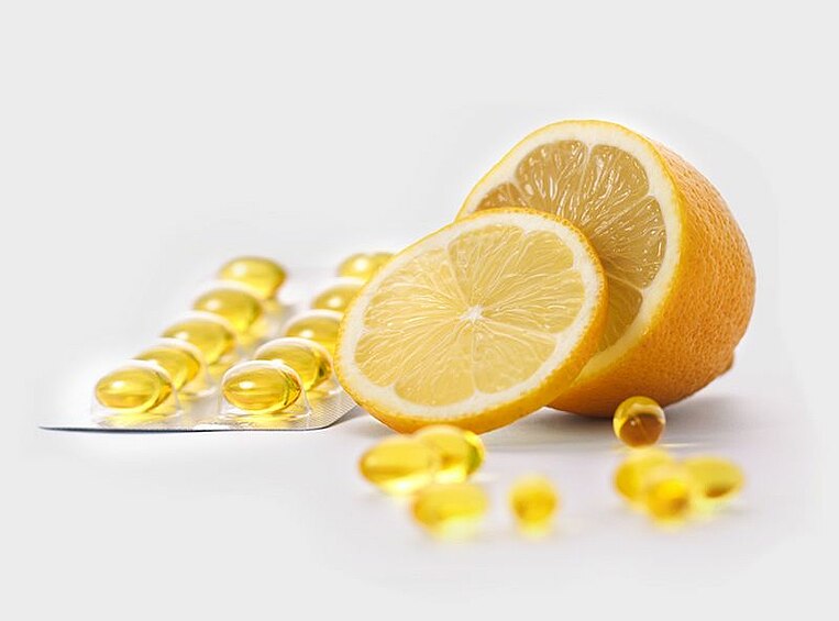 Vitamin C in Kapselform und in einer Zitrone Vitamin C in Kapselform und in einer Zitrone