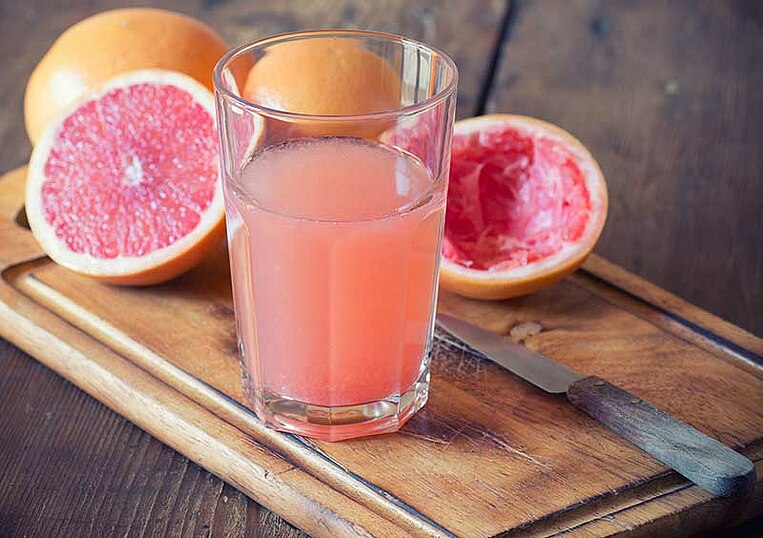 Aufgeschnittene Grapefruits und Grapefruitsaft in einem Glas Aufgeschnittene Grapefruits und Grapefruitsaft in einem Glas