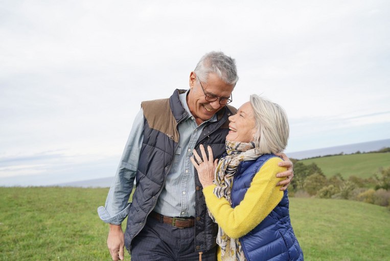 Mann und Frau stehen auf einer Wiese in den Bergen Mann und Frau stehen auf einer Wiese in den Bergen
