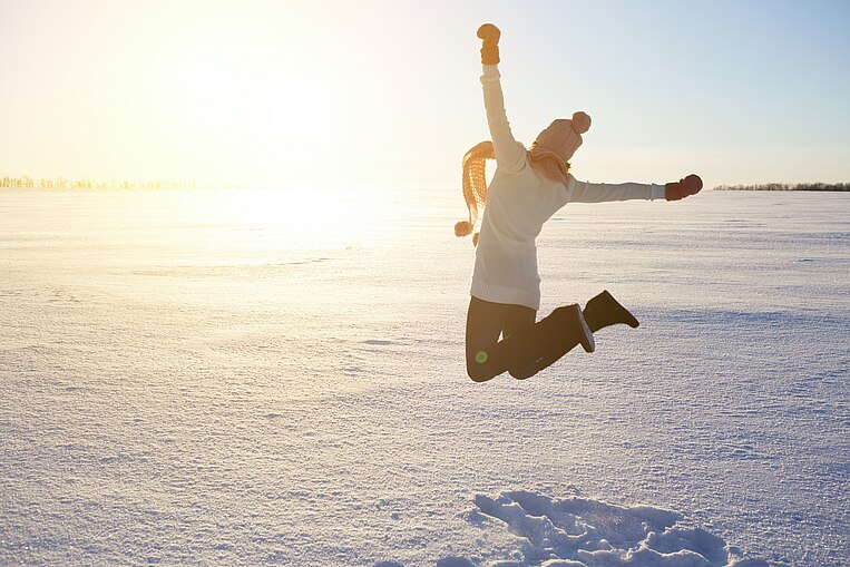 Frau springt im Schnee in die Luft Frau springt im Schnee in die Luft