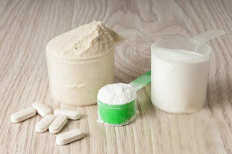 Capsule e vari cucchiai dosatori contenenti polvere su una superficie in legno Capsule e vari cucchiai dosatori contenenti polvere su una superficie in legno