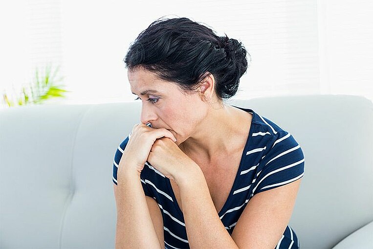 Nachdenkliche Frau sitzt auf dem Sofa Nachdenkliche Frau sitzt auf dem Sofa