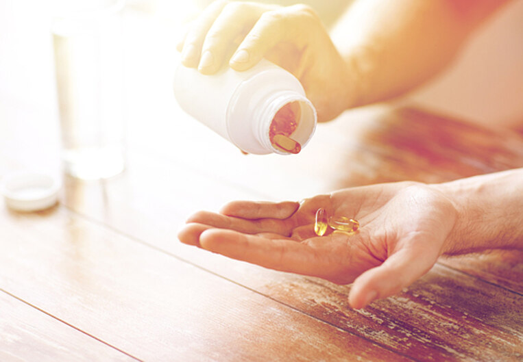 Mensch kippt sich Omega-3-Fettsäurekapseln in die Hand Mensch kippt sich Omega-3-Fettsäurekapseln in die Hand