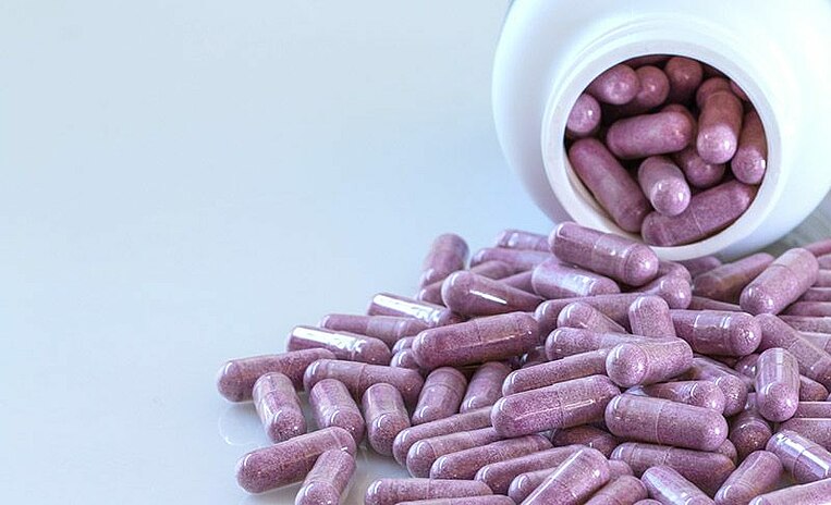 Capsule viola rovesciate fuori da un flacone Capsule viola rovesciate fuori da un flacone