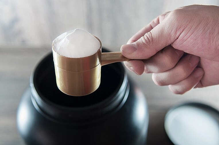 Dosatore pieno di polvere tenuto da una mano Mit Pulver befüllter Messbecher, der von einer Hand gehalten wird