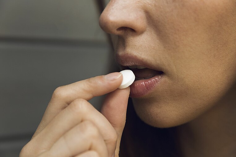 Frau nimmt eine Lutschtablette zu sich. Frau nimmt eine Lutschtablette zu sich.