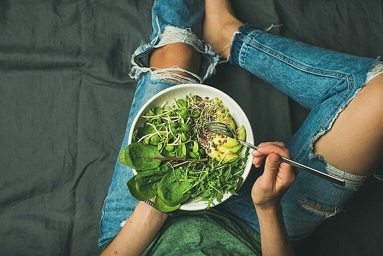 Donna con in grembo una ciotola di spinaci, rucola e avocado Frau mit einer Schale mit Spinat, Ruccola, Avocado auf dem Schoß