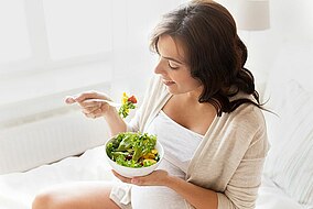 Donna incinta che mangia un’insalata
