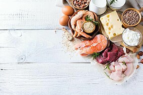 Proteinhaltige Lebensmittel wie Käse, Eier, Fischsorten, Fleisch auf einer Fläche