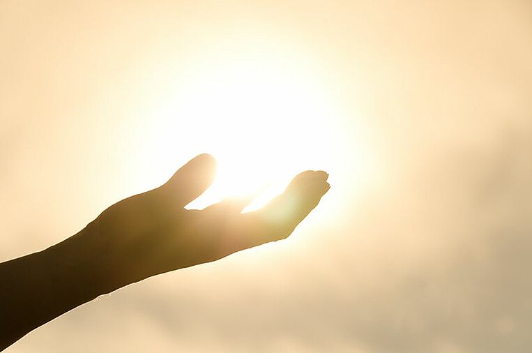 Ausgestreckte Hand mit Sonne im Hintergrund Ausgestreckte Hand mit Sonne im Hintergrund