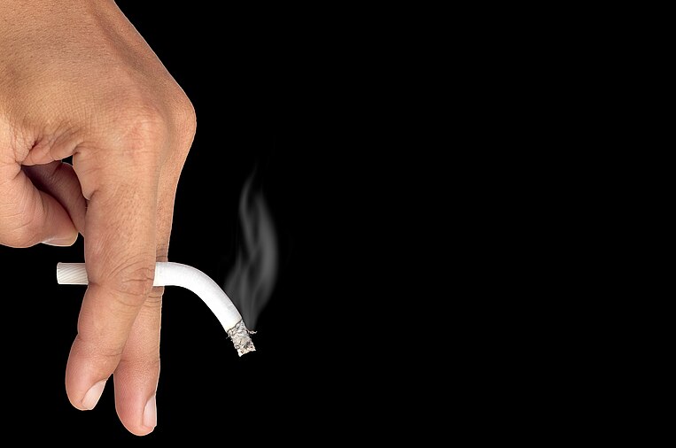 Hand hält eine rauchende Zigarette Hand hält eine rauchende Zigarette