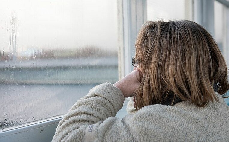 Frau schaut müde aus dem Fenster Frau schaut müde aus dem Fenster