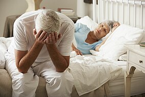 Mann sitzt enttäuscht auf der Kante von seinem Bett