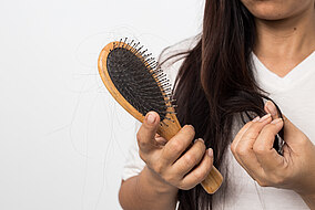 Frau hält Haarbürste in ihrer Hand