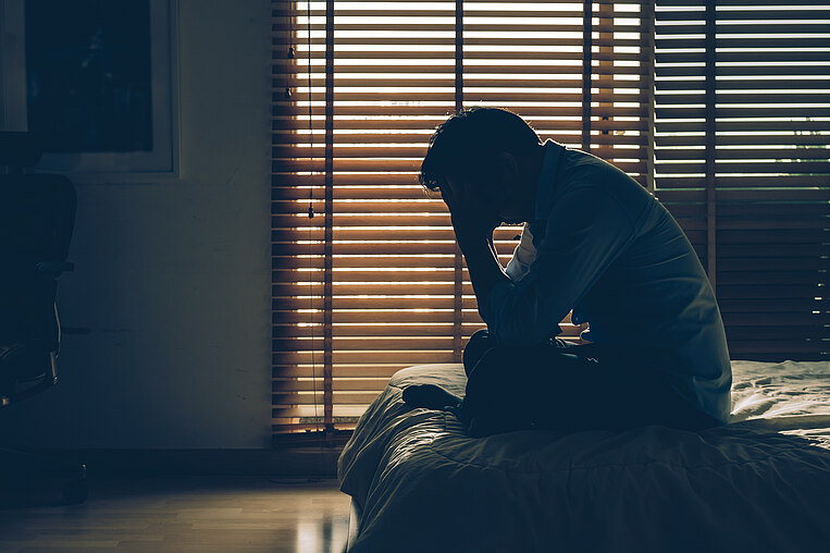 Uomo depresso seduto in una stanza buia Uomo depresso seduto in una stanza buia