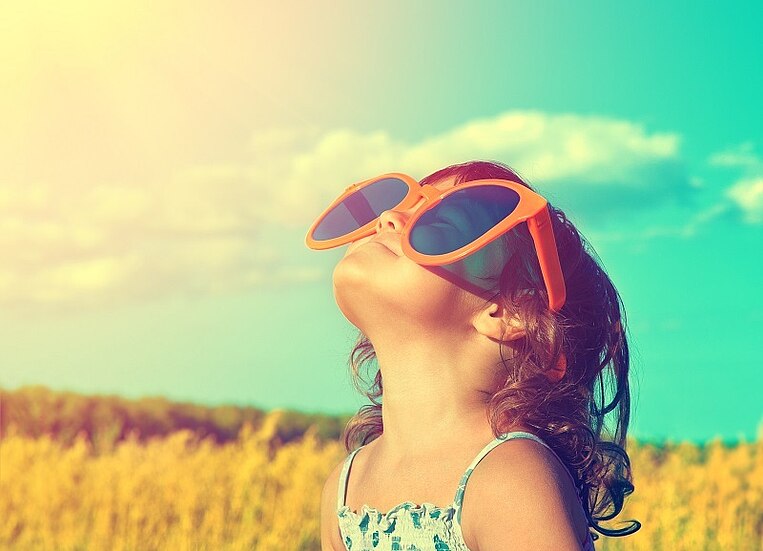 Ein Mädchen steht im Sonnenschein vor einem Feld Ein Mädchen steht im Sonnenschein vor einem Feld