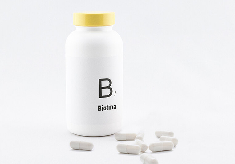 Barattolo con la scritta B7 Biotina e capsule davanti Dose mit der Aufschrift B7 Biotin und davor liegende Kapseln