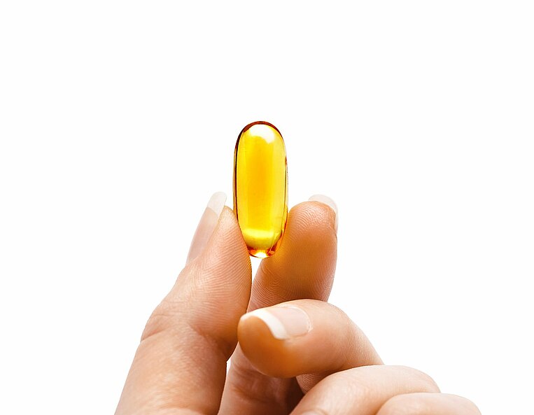 Eine Person hält eine Omega 3 Kapsel in der Hand Eine Person hält eine Omega 3 Kapsel in der Hand
