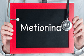 Medico che tiene davanti al petto una lavagna con la scritta "Metionina"