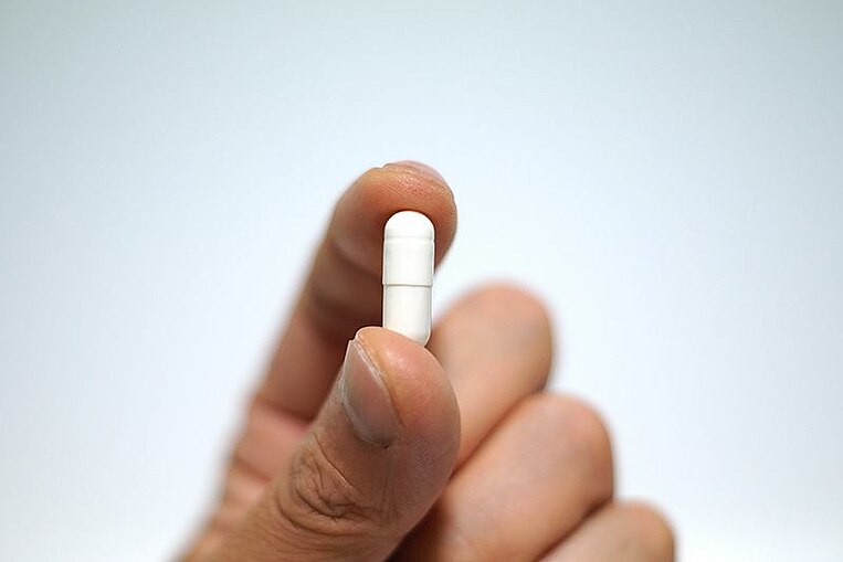 Medikamentenkapsel in Fingern