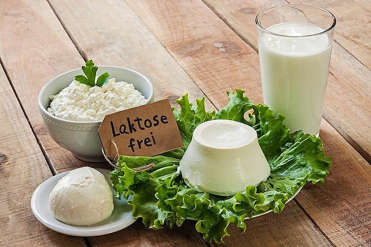 Mozzarella, Milch und Frischkäse um ein Schild mit der Aufschrift "laktosefrei" auf einer Holzfläche Mozzarella, Milch und Frischkäse um ein Schild mit der Aufschrift "laktosefrei" auf einer Holzfläche
