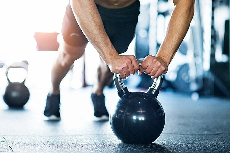 Atleta che si allena con un kettlebell Sportler trainiert mit Kettlebells