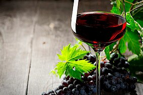 Un bicchiere di vino e un grappolo d’uva su un tavolo