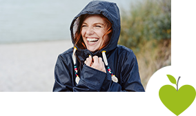 Frau steht mit Regenjacke am Strand Frau steht mit Regenjacke am Strand