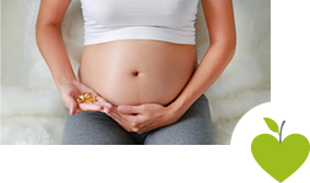 Eine schwangere Frau hält Omega-3-Präparate neben ihren Bauch Eine schwangere Frau hält Omega-3-Präparate neben ihren Bauch