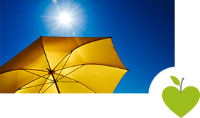 Ein gelber Sonnenschirm vor einem strahlend blauen Himmel mit Sonne Ein gelber Sonnenschirm vor einem strahlend blauen Himmel mit Sonne