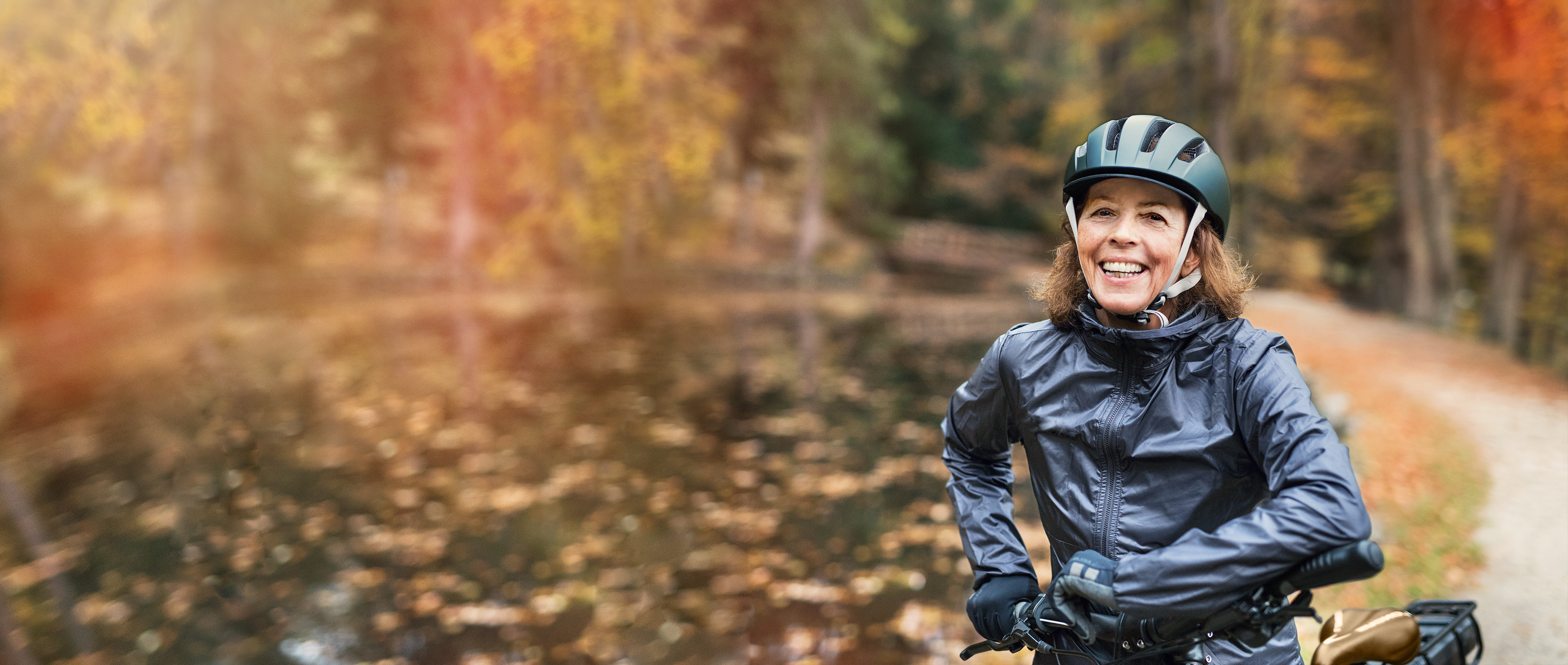 An active elderly cyclist standing on a forest path in autumn